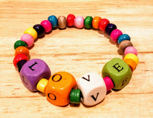 Load image into Gallery viewer, Our young ladies deserve all of the LOVE we can give them! This fun colored wood beaded bracelet has cube beads stamped with LOVE, individually. The LOVE beads are surrounded by colorful tube shaped beads and is completed with beautifully colored round beads.   The bracelets are made of stretch wire and come in sizes 6&quot; &amp; 6-1/2&quot;. If you would like a different size, please contact us.  *** Please note that the colors are random with regards to all of the bead types. ***
