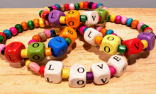 Load image into Gallery viewer, Our young ladies deserve all of the LOVE we can give them! This fun colored wood beaded bracelet has cube beads stamped with LOVE, individually. The LOVE beads are surrounded by colorful tube shaped beads and is completed with beautifully colored round beads.   The bracelets are made of stretch wire and come in sizes 6&quot; &amp; 6-1/2&quot;. If you would like a different size, please contact us.  *** Please note that the colors are random with regards to all of the bead types. ***
