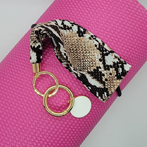 These swank keychains are functional and spirited! Show off your fun personality! No reason to carry your whole purse to class or the gym. Simply slip the soft fabric over your wrist and your keys/key cards/card wallet are at your fingertips in seconds. In addition to the split ring, these key chains also have a detachable key ring, with a tag charm you can personalize, for added convenience.   3 fabrics - Brown snake skin, Mustard white polka dot & Leopard